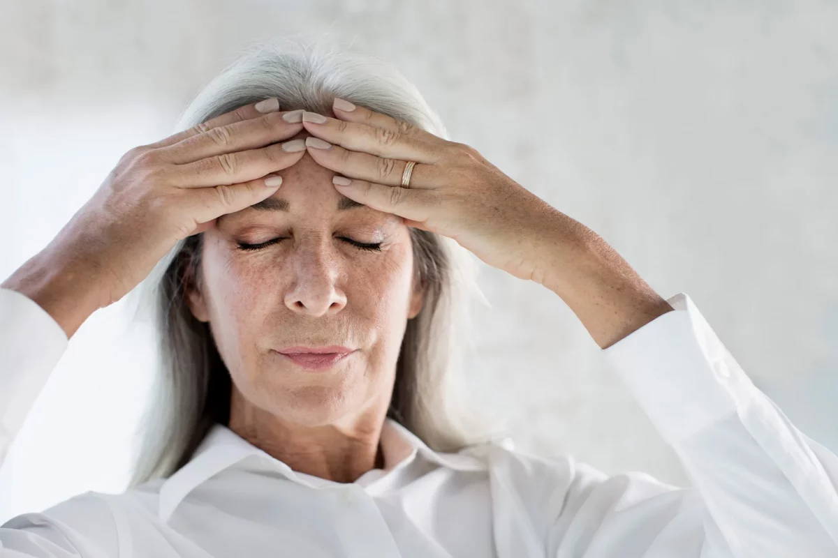 Frau mit geschlossenen Augen und Händen an der Stirn – Symbol für Entspannung und Achtsamkeit zur Reduktion von oxidativem Stress